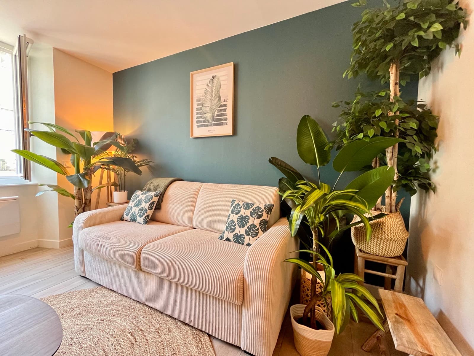 Salon cosy avec canapé, mur vert et plantes tropicales, Jungle Haven à Romans