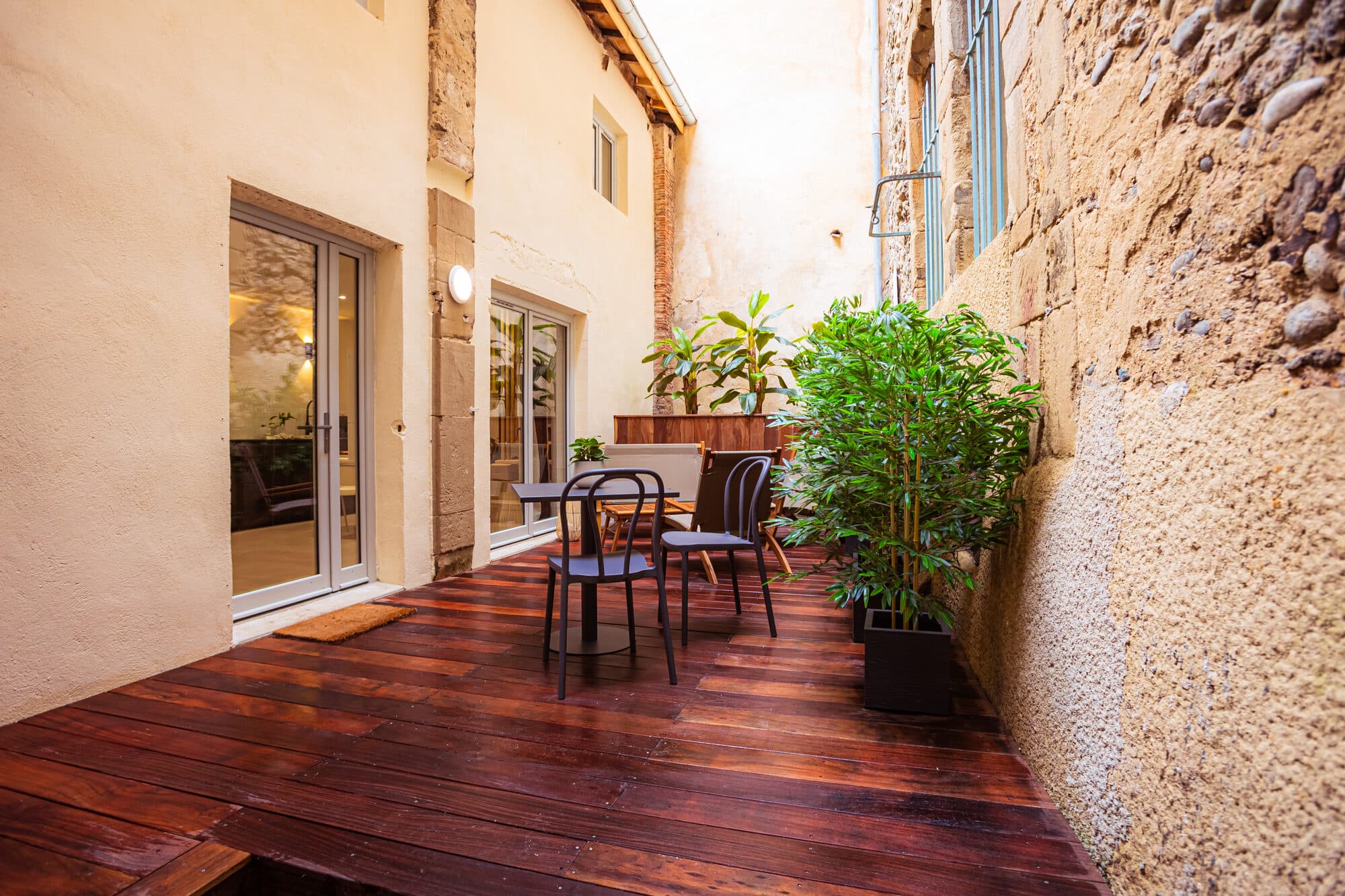 Terrasse en bois exotique entourée de bambous et bananiers, cour privative de Zen Haven